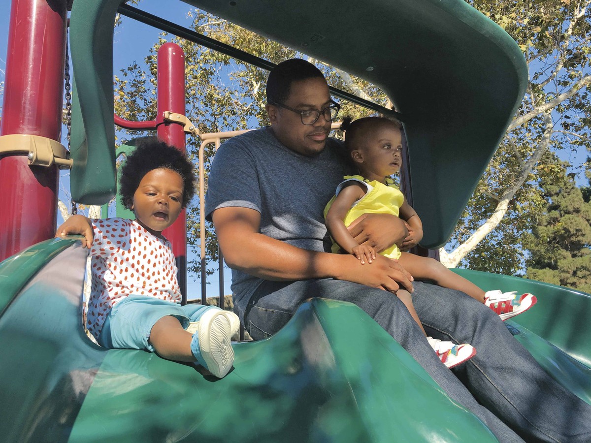 dad and two small kids sitting together at the top of the playground slides