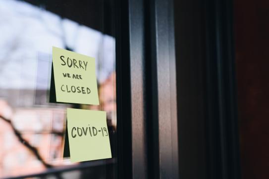 Post-it notes on a store's front door read: "Sorry we are closed" and "COVID-19"